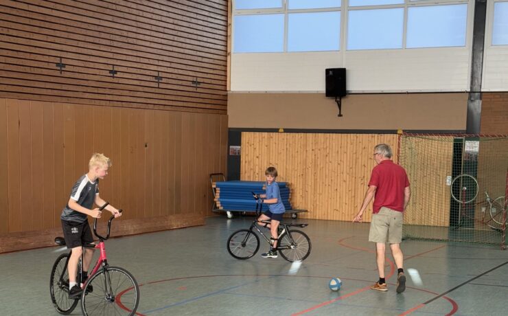 2 Radball spielende Kinder plus Übungsleiter